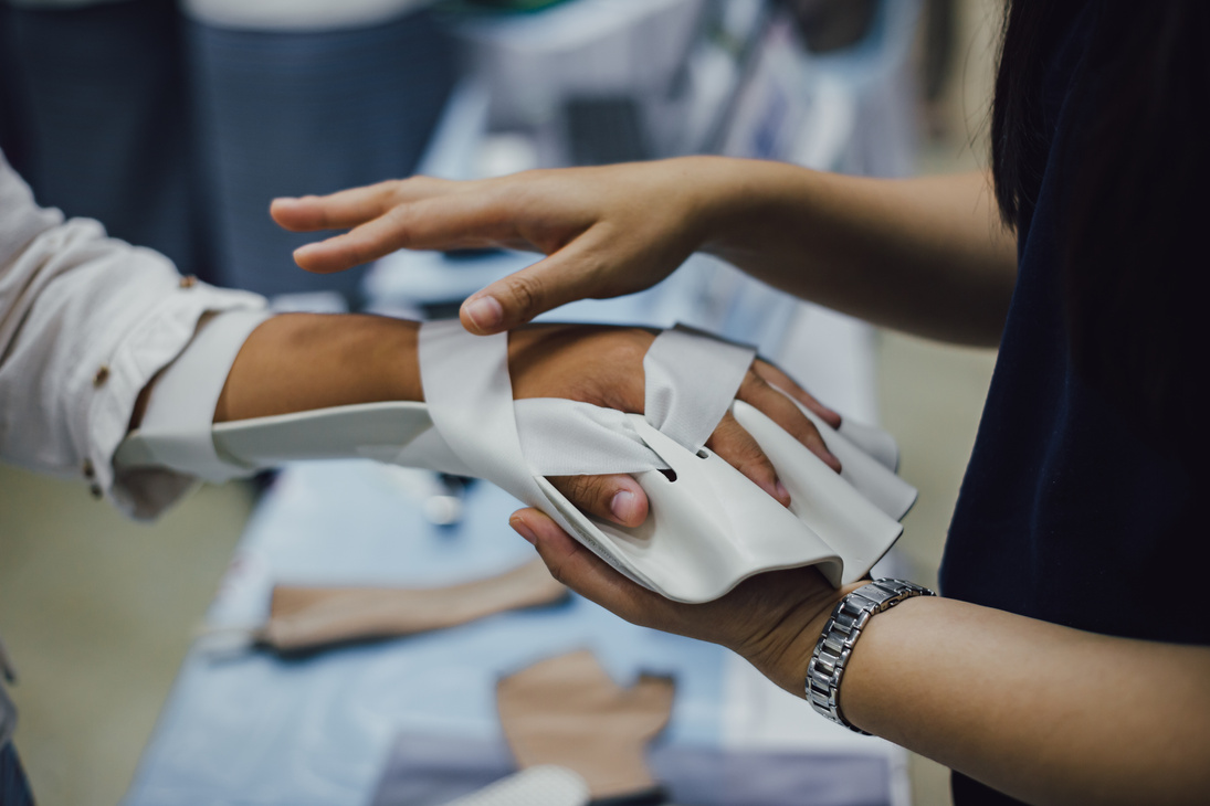 Therapist making assistive device for immobilize patient hand. Splint service for hand injury rehabilitation of occupational therapy clinic.