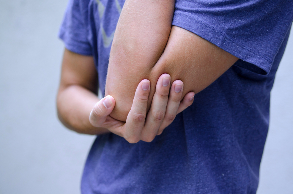 Young man sprained his arm and have elbow pain.Holding helpless his arm cubit