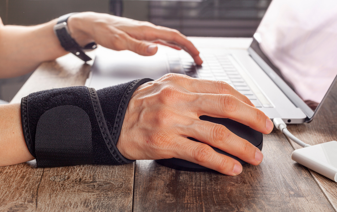 Hand Wearing Wrist Support Using a Laptop and Mouse